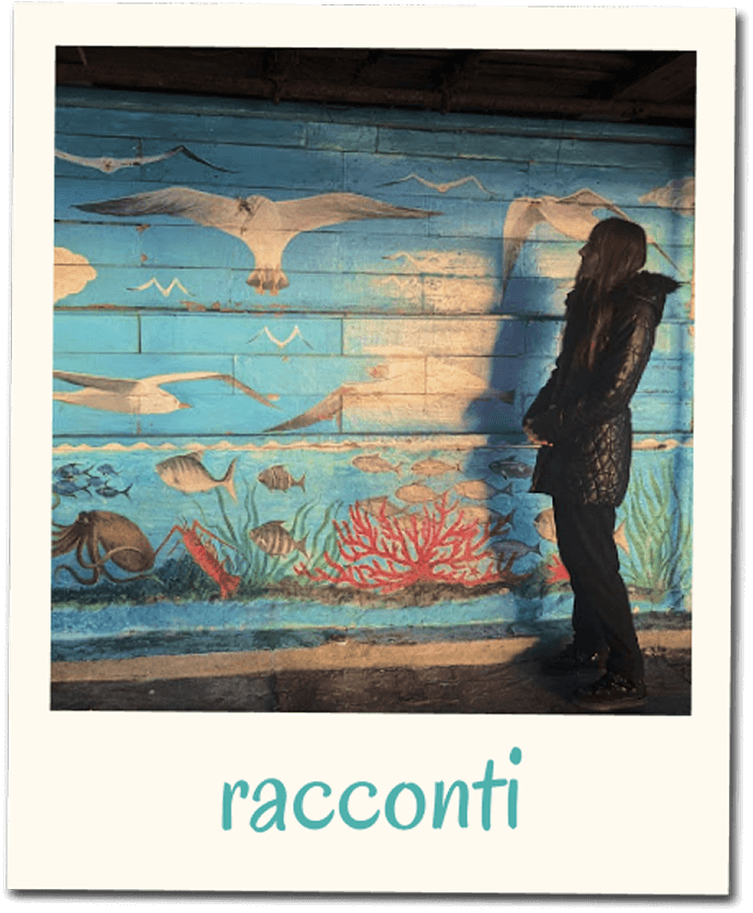 Card del servizio racconti con fotografia in stile polaroid di una donna di profilo davanti a un murale marino, con la scritta ‘racconti’ nella cornice inferiore.